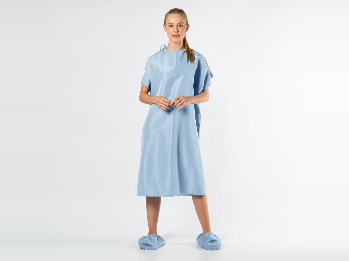 Mujer con bata de paciente azul claro, de cuerpo entero
