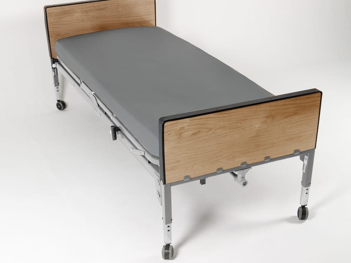 Cama hospitalaria con protector de colchón gris