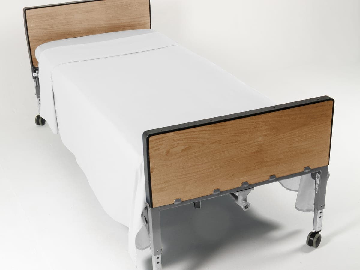 Cama hospitalaria tendida con sábana blanca